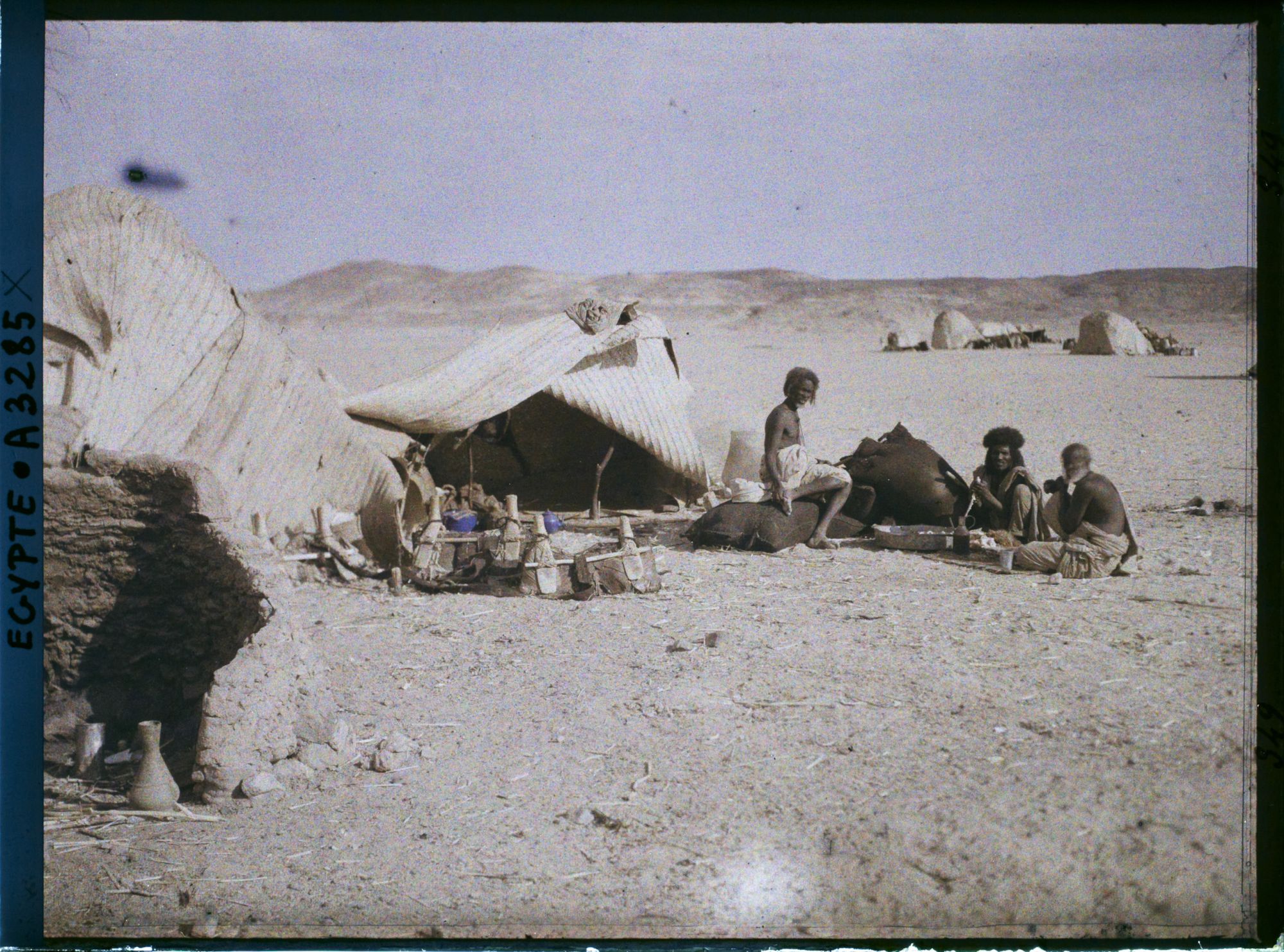 Image représentant Trois hommes  null bishari assis devant leurs habitations