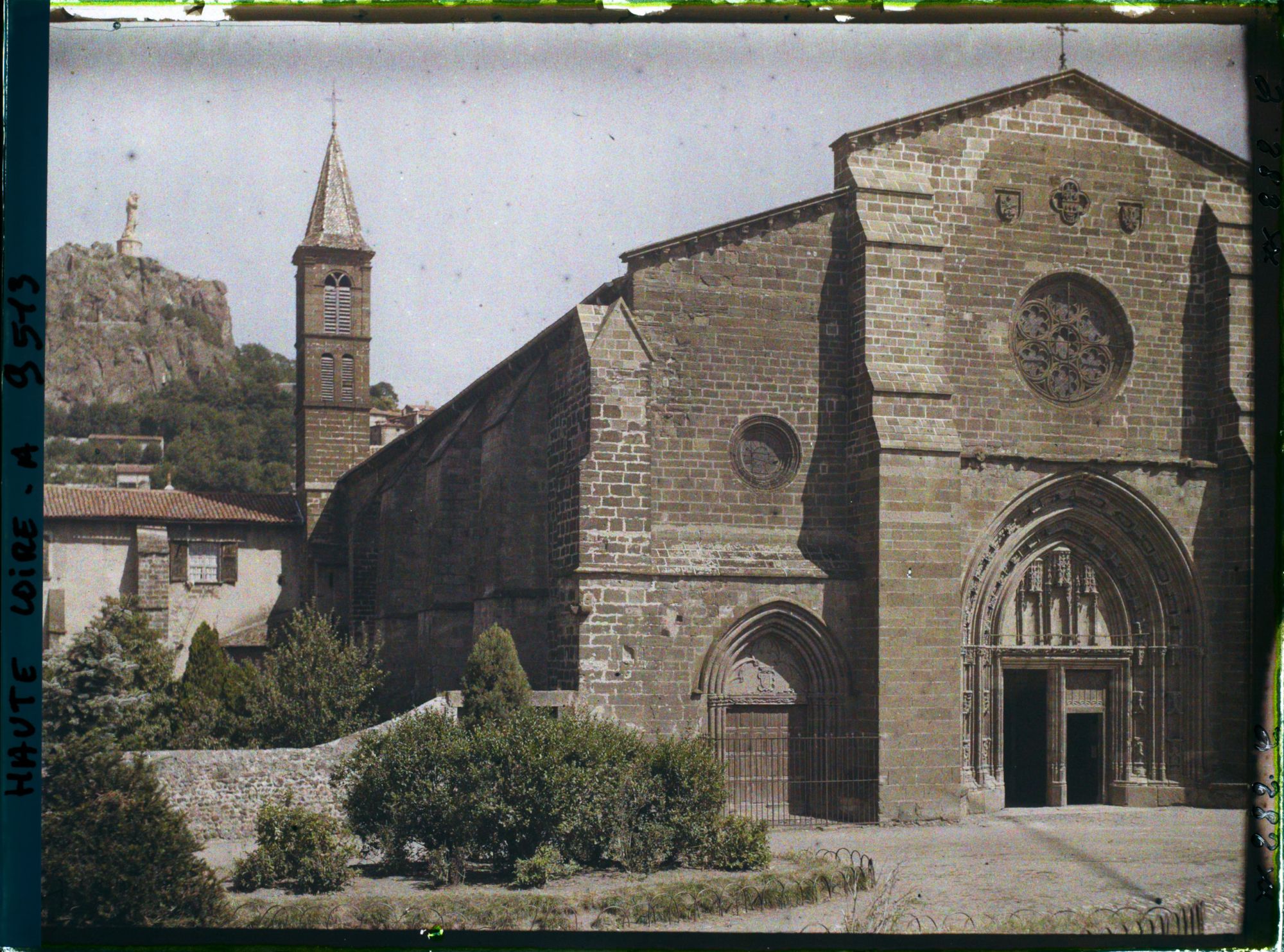 Image représentant La façade et le clocher de l'église Saint-Laurent, avec à l'arrière-plan, le rocher de la Vierge et la statue de Notre-Dame-de-France