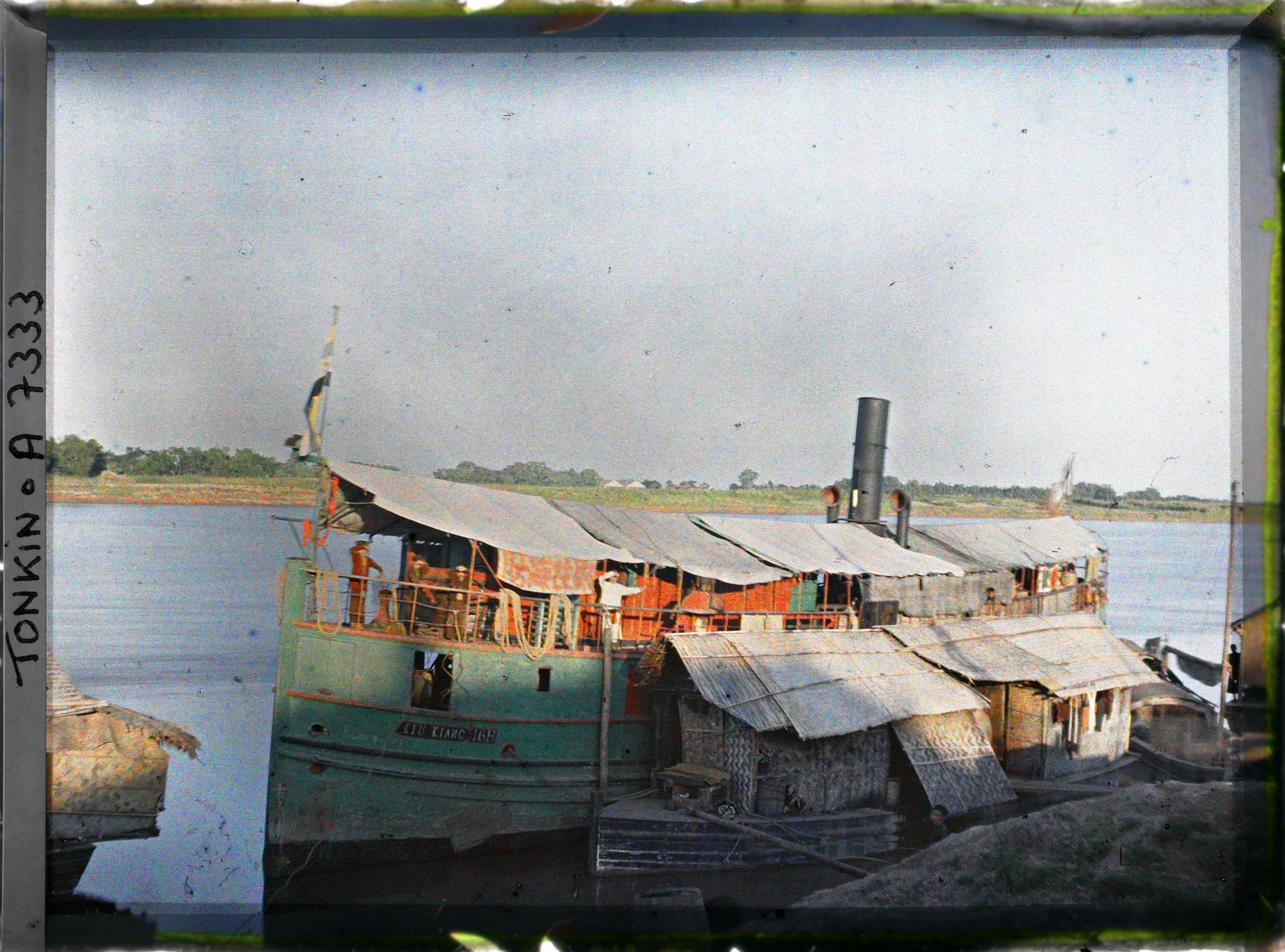 Image représentant Une chaloupe chinoise amarrée le long de maisons flottantes au bords du Fleuve Rouge, le soir