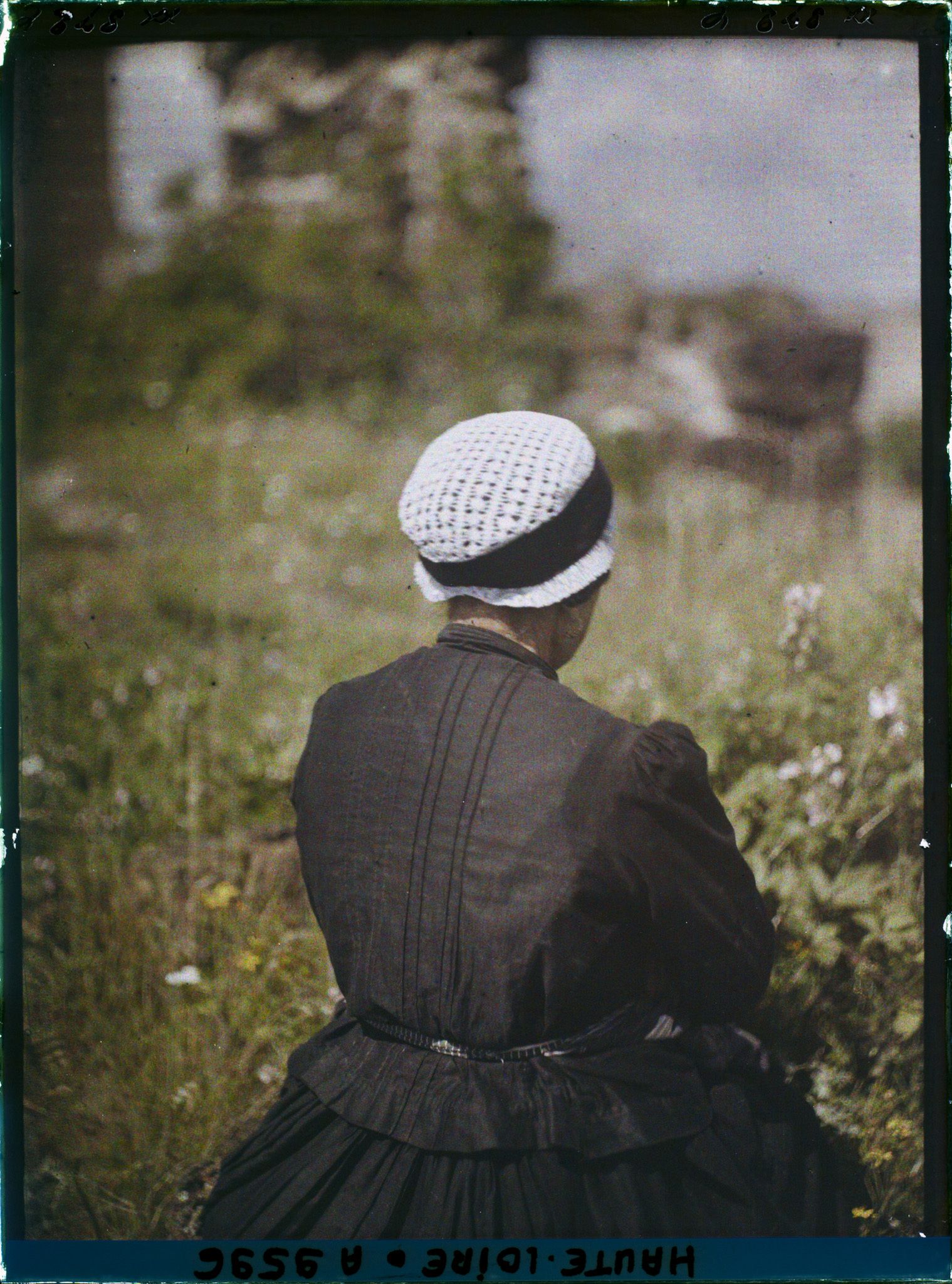 Image représentant Femme de dos portant un bonnet traditionnel du Puy en dentelle et ruban