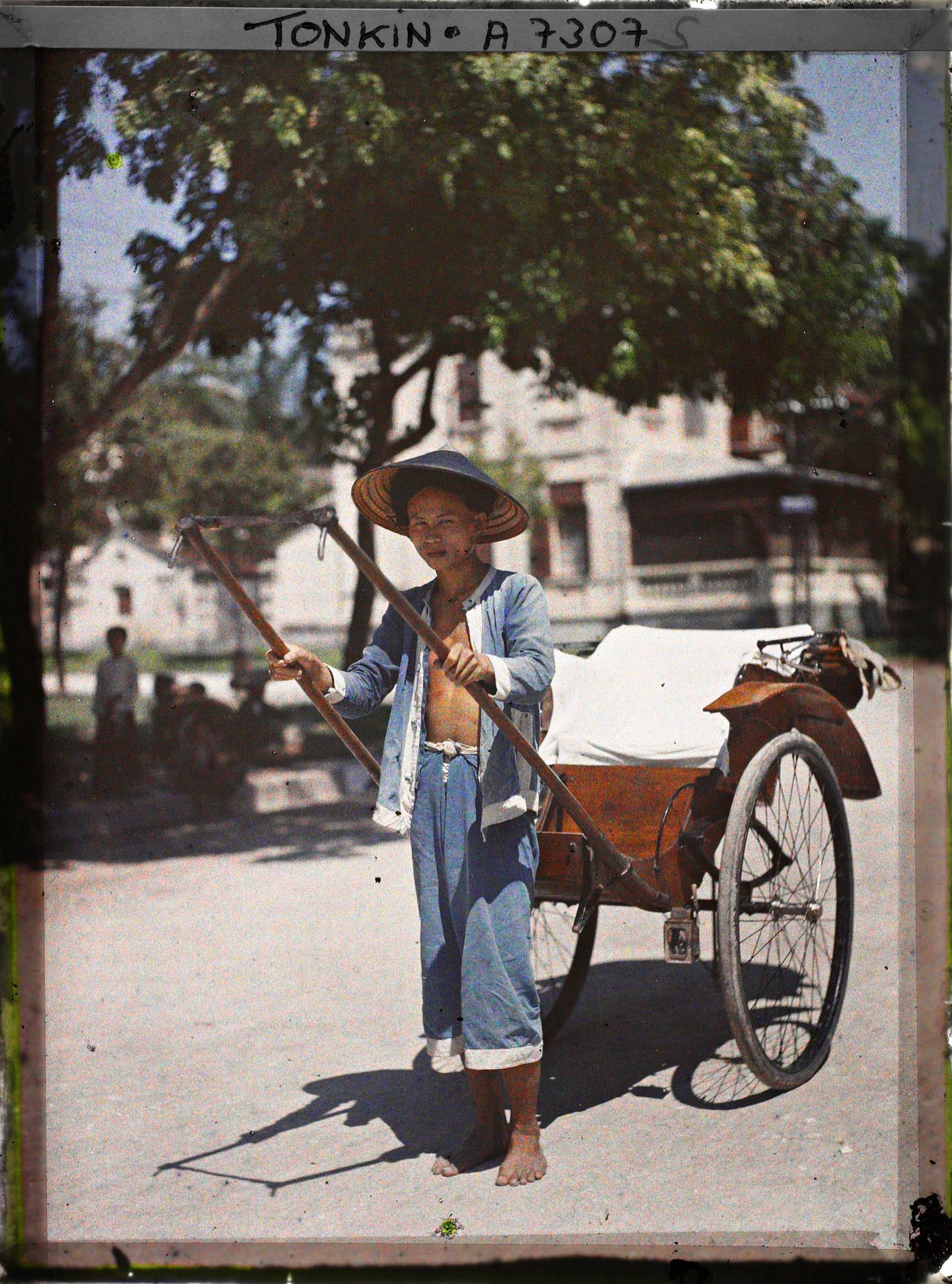 Image représentant Un pousse-pousse à roues caoutchoutées et son tireur, vêtu et coiffé de bleu