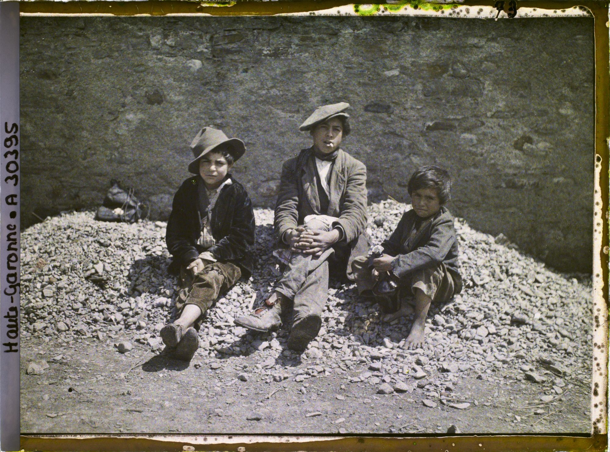Image représentant trois enfants espagnols assis sur un tas de cailloux