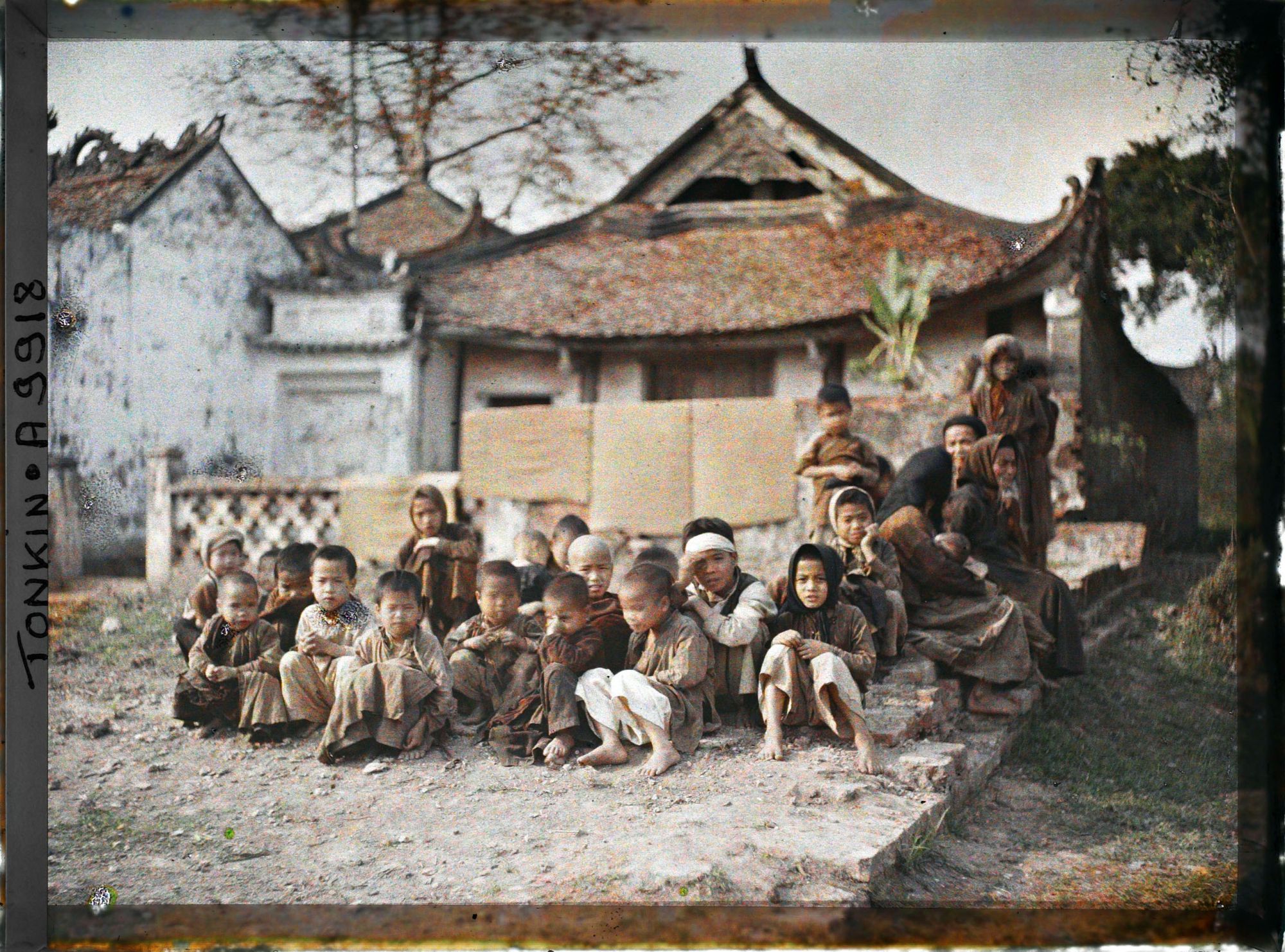 Image représentant Un groupe de villageois (principalement des enfants) assis devant le temple bouddhique, dit " Pagode de l'abattoir "