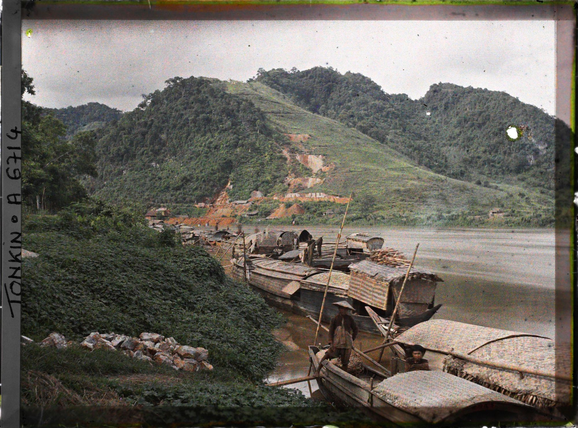 Image représentant Des sampans ancrés au bord de la rivière Claire, à l'arrière-plan, les mines de zinc de Trang-da