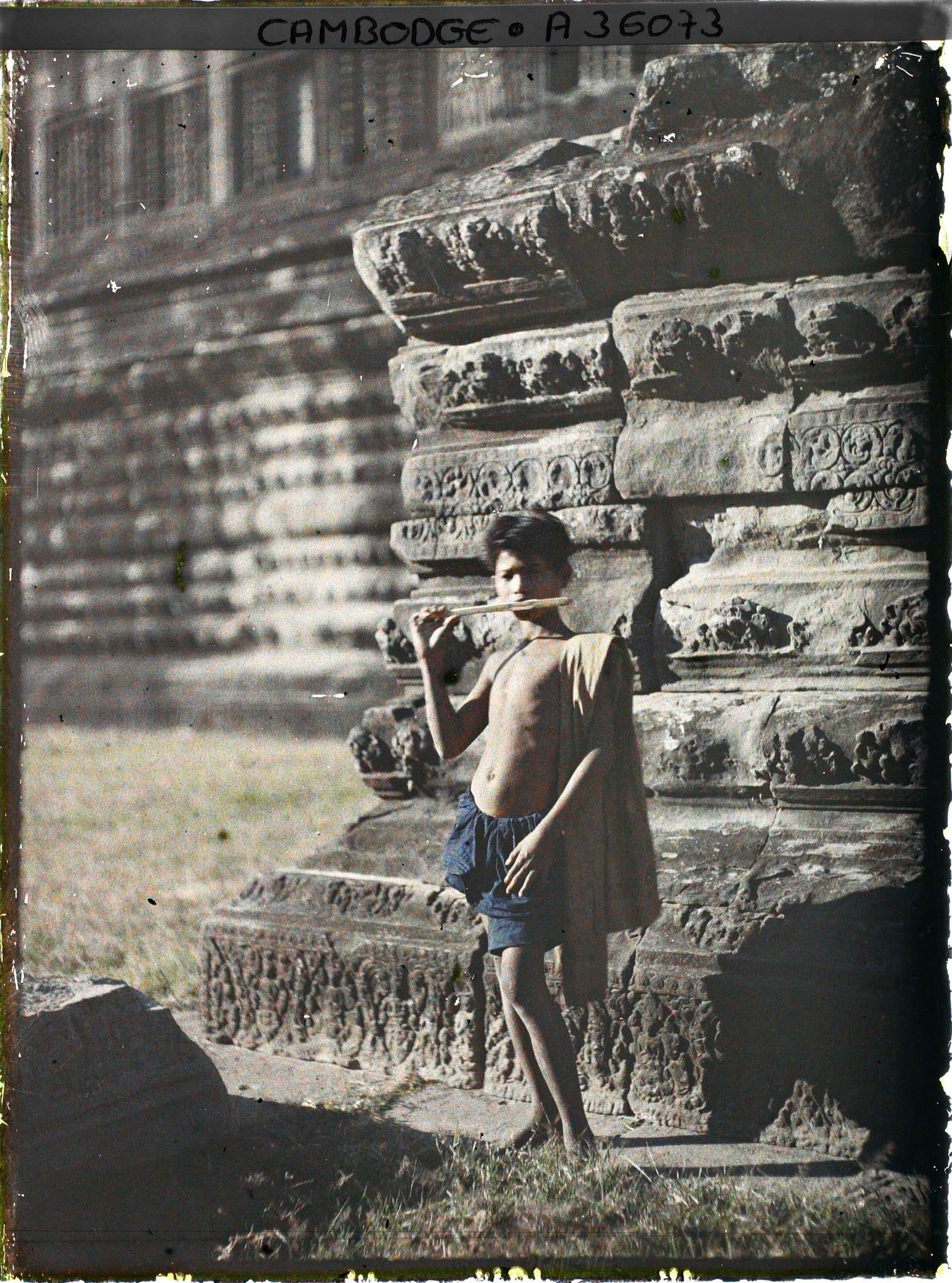 Image représentant Un jeune joueur de flûte, au pied de la galerie pourtournante formant le deuxième niveau du temple