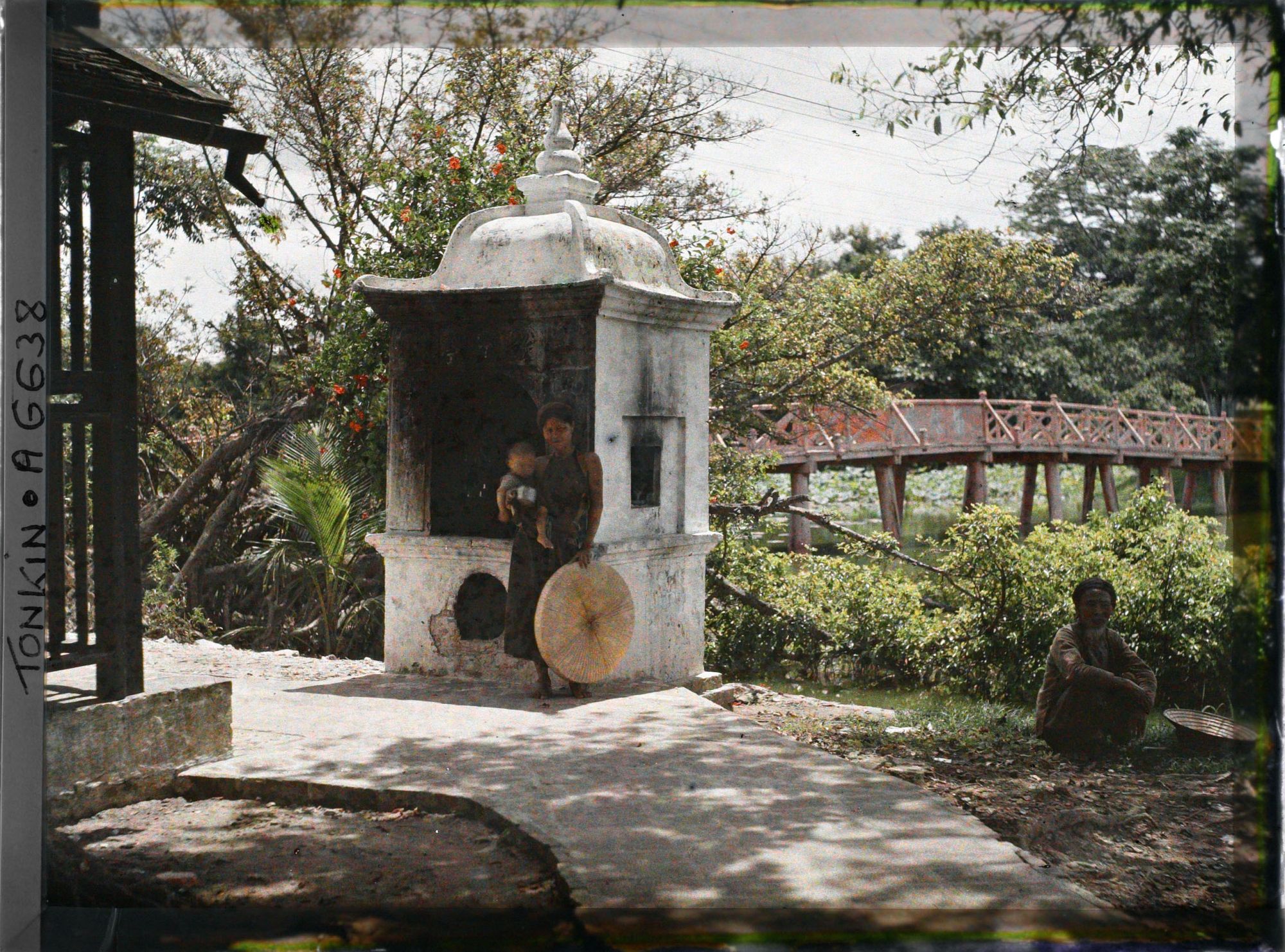 Image représentant Une femme et enfant devant un édicule près de la passerelle conduisant au temple Ngoc-so'n (appelé par les Européens "Pagode des Pinceaux") situé sur "l'île de Jade" du Petit Lac