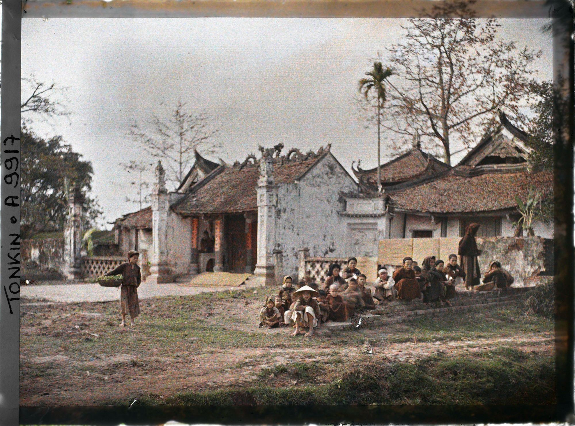 Image représentant Un groupe de villageois (principalement des enfants) assis devant le temple bouddhique, dit " Pagode de l'abattoir "