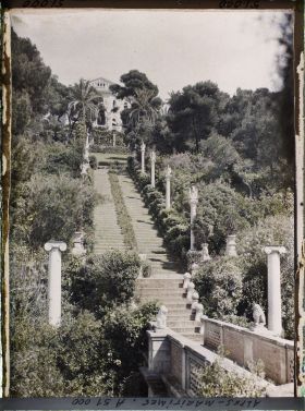Image représentant La villa Cypris dominant le grand escalier fleuri du jardin ponctué de sculptures et la passerelle