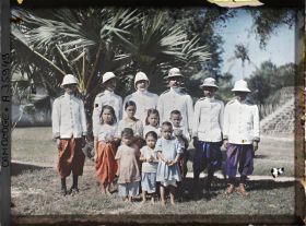 Image représentant Un fonctionnaire du protectorat français entouré de fonctionnaires cambodgiens, accompagnés d'enfants