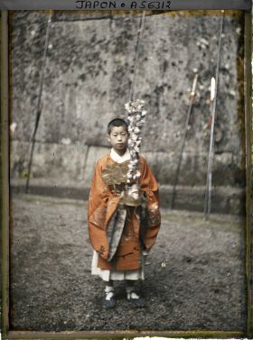 Image représentant Jeune garçon costumé, portant entre ses mains un casque orné d'une branche de prunier fleuri, lors de la fête du sanctuaire Tôshôgu