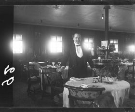 Image représentant Herr K. Nagel, Maître d'hôtel posant dans la salle du restaurant Ritz-Carlton des passagers des 1eres classes