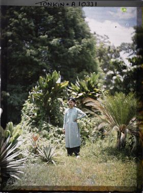 Image représentant Une jeune élégante, épouse d'Européen, en turban et tunique vert pâle, dans un jardin