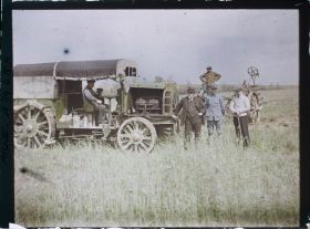 Image représentant Hommes prenant la pose aux côtés d'un camion destiné à tracter la charrue visible à l'arrière plan