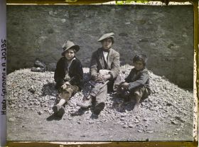 Image représentant trois enfants espagnols assis sur un tas de cailloux