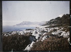 Image représentant La villa Kahn dite villa Zamir, vue depuis le rivage où roches et végétation se mêlent